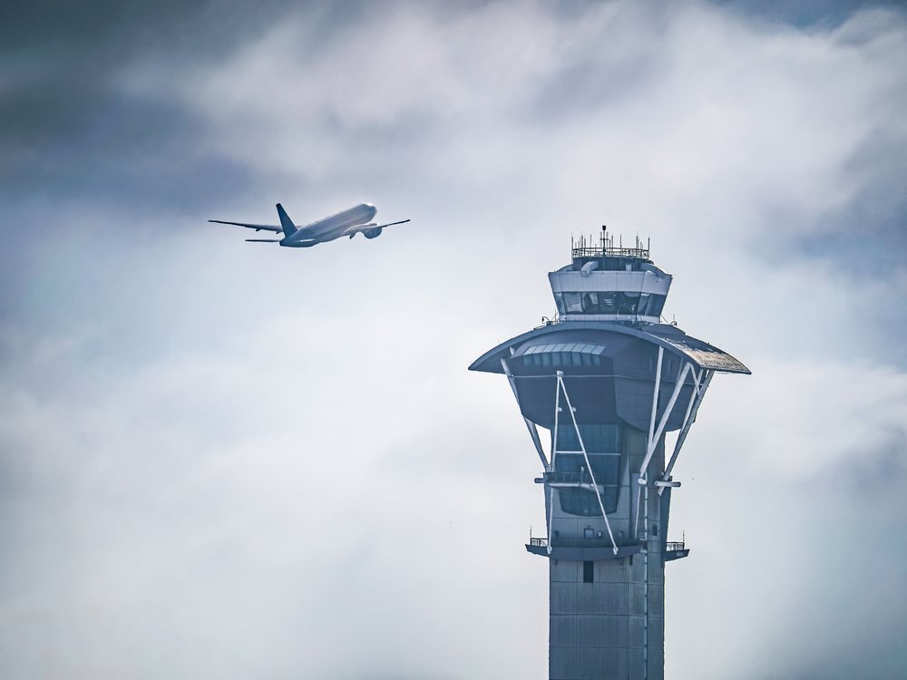 An airport control tower as an aircraft departs.