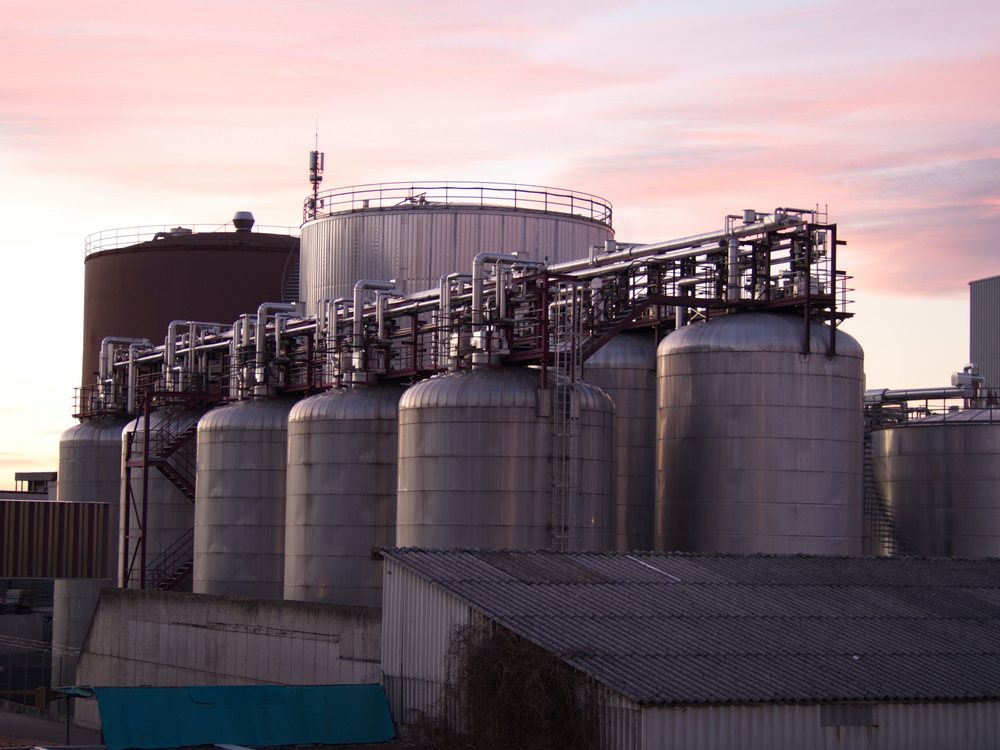 An oil and gas storage and processing facility at dusk.